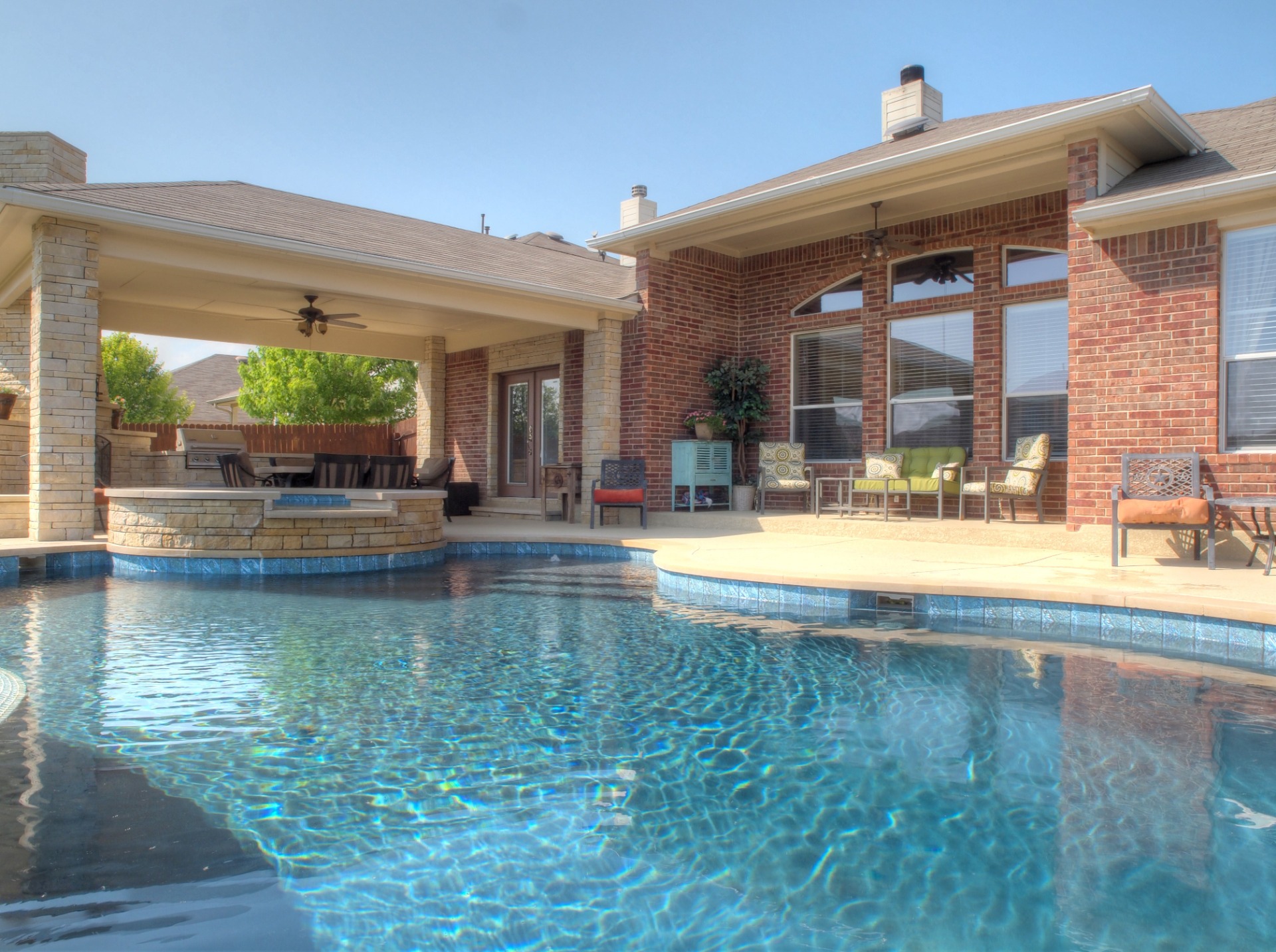 Custom freeform pool and spa with 6"x6" waterline tile, faux negative edge, custom gunite and mosaic slide/waterfall, and outdoor kitchen with fireplace.