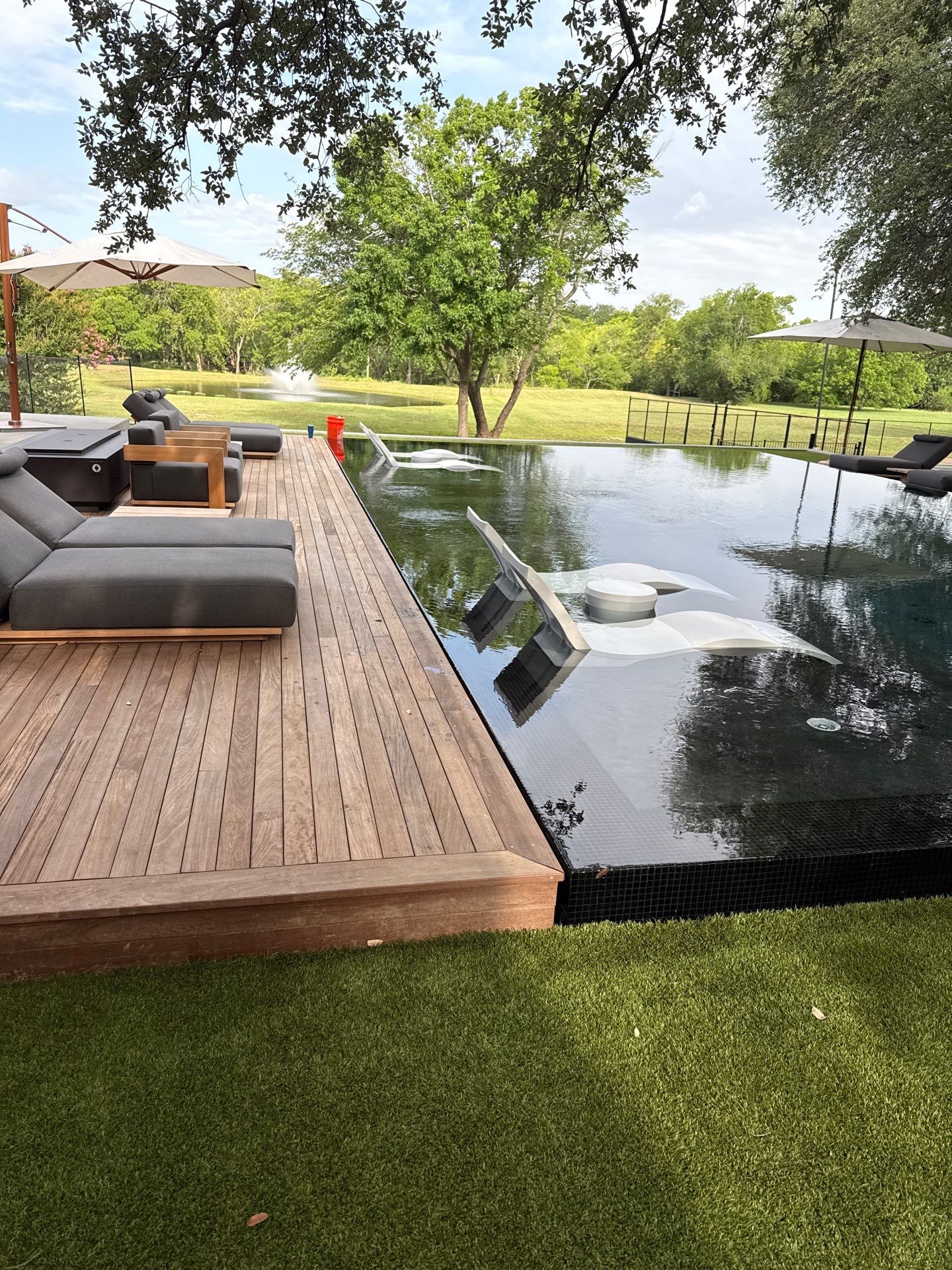 Perimeter Overflow Pool and Spa with Bisazza black mosaic waterline and beam tile. Ipe wood deck and artificial turf covers the perimeter overflow catch basin.