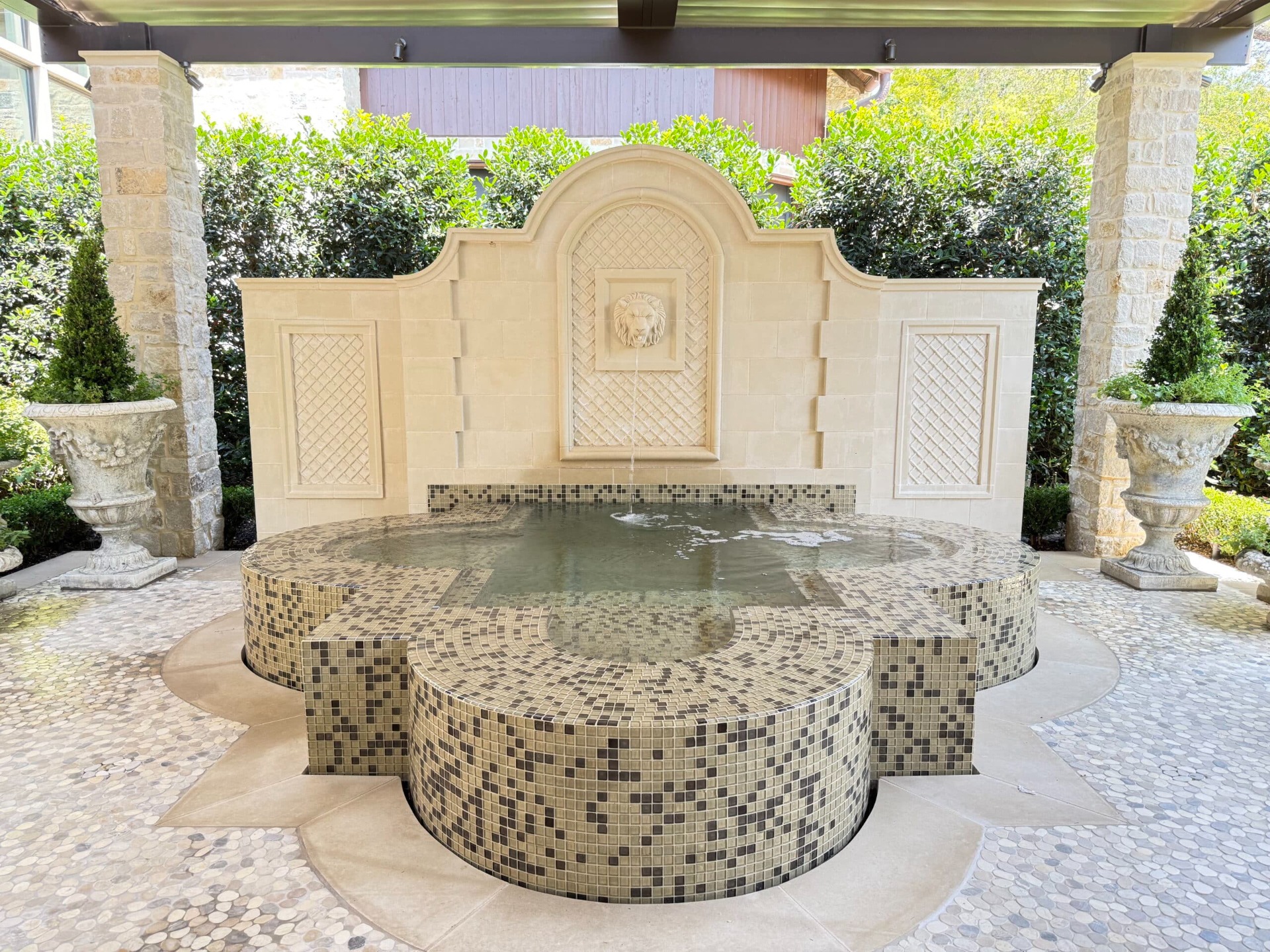 Perimeter overflow spa with Waterway Jets Captain Seats, all mosaic tile finish, raised wall with custom hand carved lion head sconce.